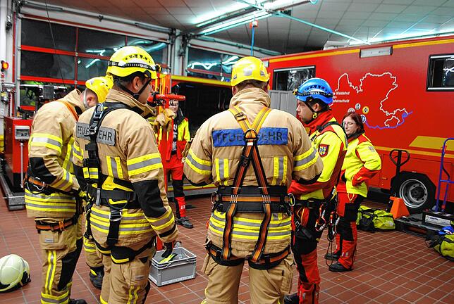 Sicherheit geht vor: Jan-Hendrik Weiland (mit blauem Helm) erklärt den Feuerwehrmännern, wie sie die Kletterausrüstung anlegen. Ganz ...