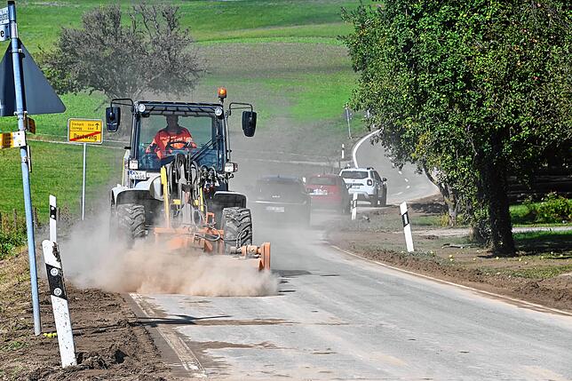 Ein Fahrzeug der Straßenmeisteri wirbelt beim Reinigen des getrockeneten Schlamms ordentlich Staub auf. Der Schlamm kam von einem Feld ...