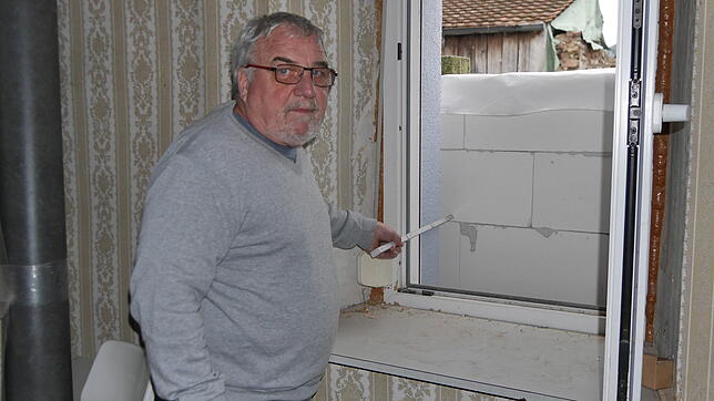 Günther Hottinger zeigt mit einem Metermaß, wie gering der Abstand des Zimmerfensters zur Außenwand der Garage ist. Der Blick aus dem ...