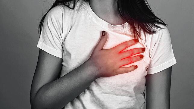 Eine Frau hält sich die Brust. Der Schmerz im Brustkorb, der typisch für den Herzinfarkt ist, tritt bei Frauen seltener auf als bei ...