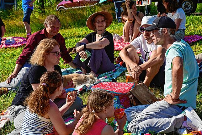 Die Teilnehmer genießen ein Picknick in freier Natur und lauschen dazu der Klangperformance, die mal als Chor, mal als HeavyMetal-Sound, ...