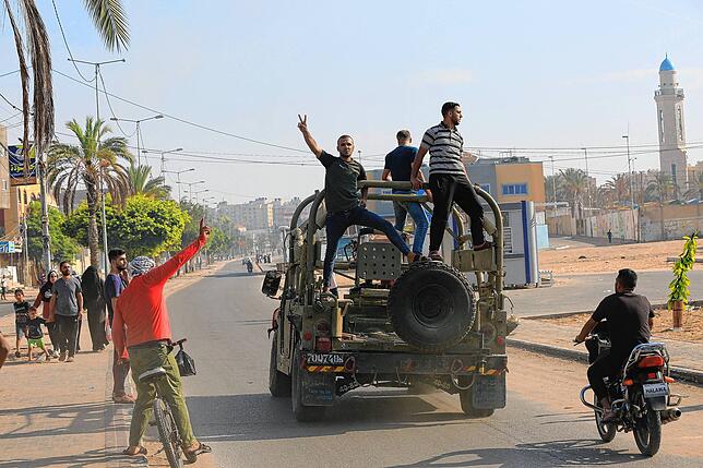 Palästinenser fahren auf einem israelischen Militärfahrzeug, das von einem von Hamas-Kämpfern überrannten Armeestützpunkt in der Nähe ...