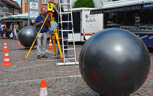 So groß sollen die Bronzekugeln werden: David Fuchs nimmt im Juli 2024 mit Attrappen Maß in der Marktstraße, während eines ...