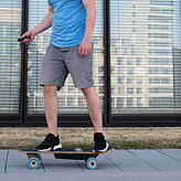 In der Hand eine kleine Fernbedienung und unter dem Brett der Akku. Bei elektrischen Skateboards ist keine Muskelkraft nötig.