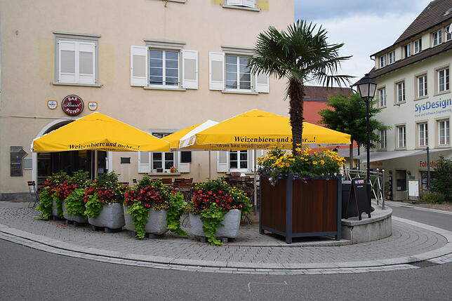 So sieht die Stelle am Marktplatz heute ohne Brunnen aus. Es ist der Außenbereich eines Lokals.