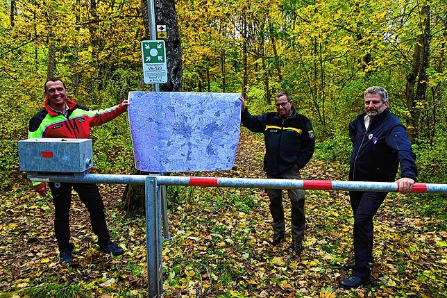 Roland Brauner (links) und Jörg Hammes vom Forstamt zeigen vor dem Rettungspunkt-Schild die große Karte, auf denen die Rettungspunkte in ...