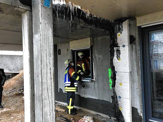 Feuerwehrleute inspizieren nach den Löscharbeiten die Lage rund um das Gebäude.