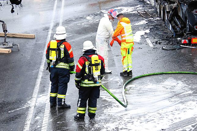 Ein Hochvoltspezialist lässt sich Spezialhandschuhe überstülpen, die auch die Feuerwehrleute trugen, bevor sie die Wracks an die Gurte ...