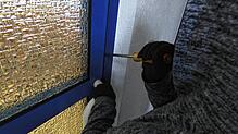 Ein Einbrecher macht sich an einer Tür zu schaffen (Symbolbild).
