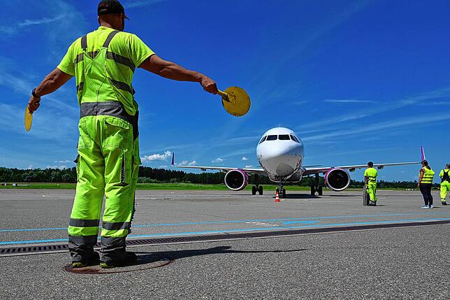 Ein Mitarbeiter des Bodensee-Airports weist das Passagierflugzeug zu seinem Platz.