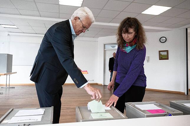 Winfried Kretschmann (Bündnis 90/Die Grünen, l) bei der Stimmabgabe zur Kommunal- und Europawahl im Rathaus im Sigmaringer Stadtteil Laiz
