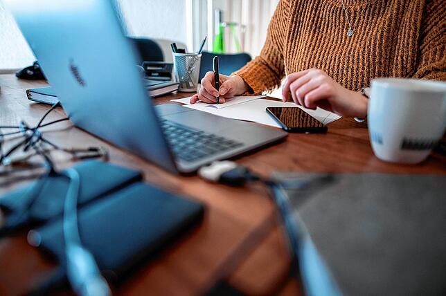 Eine Frau sitzt mit einem Laptop an einem Tisch im Homeoffice. Der neue Alltag ist für viele nicht mehr wegzudenken.