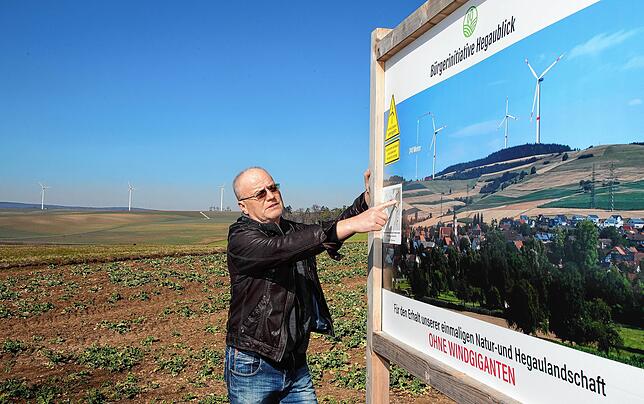 Siegfried Münzer vor einer Protesttafel am geplanten Windkraft-Standort oberhalb von Watterdingen. Im Hintergrund die Leipferdinger ...