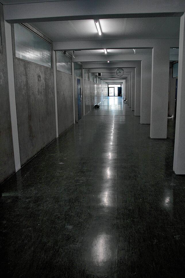 Die Betonstützen in den Gängen wurden einheitlich hellgrau gestrichen, der Linoleum-Boden erhalten. Moderne LED-Lichtleisten beleuchten ...