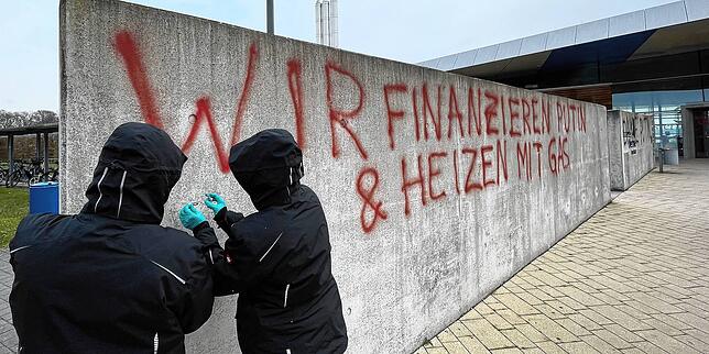 Die Spurensicherer bei der Arbeit. Hier nehmen sie gerade Farbproben von der Schrift auf einer der Sichtbetonmauern auf dem Vorplatz.