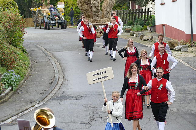 Die Mundelfinger Landjugendlichen führen mit der Erntedankkrone und einem Mottowagen den Umzug durch die Ortschaft an.