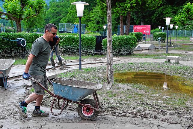 Mit dem Schubkarren wird der Schlamm von der Minigolfanlage gekarrt und zurück in den Rhein geschüttet.
