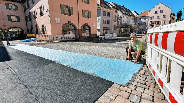 Andree Pohl (rechts) und seine Kollegen von der Firma Schöppeler decken die frisch verfugten Flächen auf dem Villinger Münsterplatz zum ...