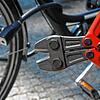 Unser Symbolbild zeigt einen Fahrraddieb mit einem Bolzenschneider vor einem abgeschlossenen Drahtesel.