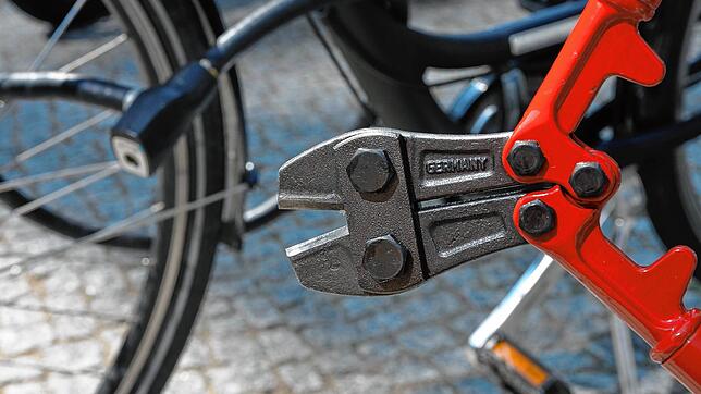 Unser Symbolbild zeigt einen Fahrraddieb mit einem Bolzenschneider vor einem abgeschlossenen Drahtesel.