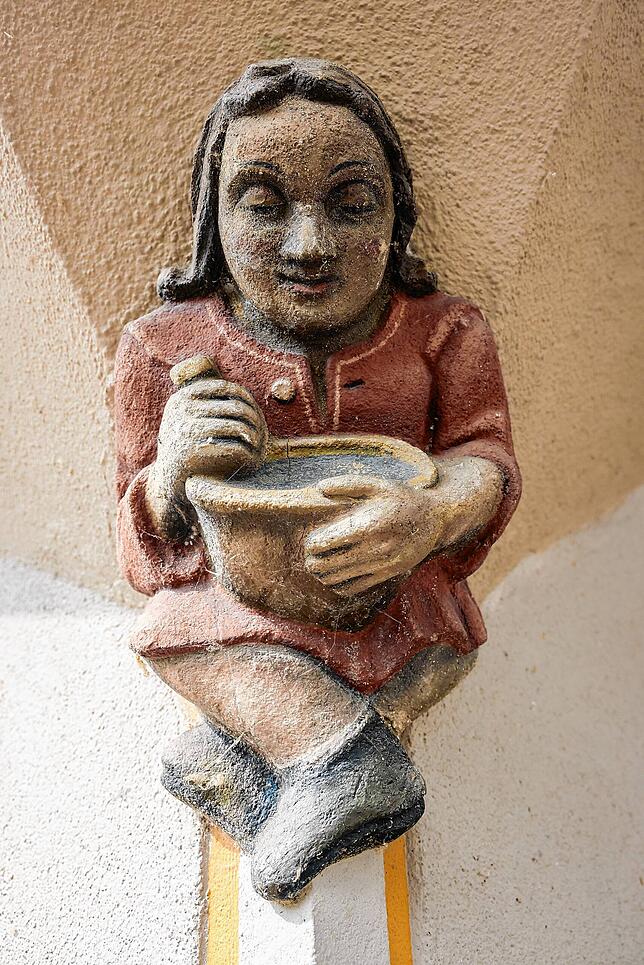 Mit übereinandergeschlagenen Beinen sitzt diese Figur an einer Fassade in Radolfzell. Aber welcher?
