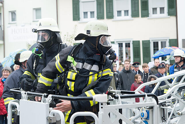 Feuerwehrleute mit Atemschutzgeräten sind bereit zur Fahrt nach oben mit der Drehleiter.