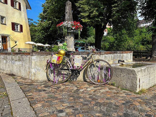 Am Brunnen im Schweizer Laufenburg steht ein Fahrrad, das sich thematisch am Märchen vom Froschkönig orientiert.