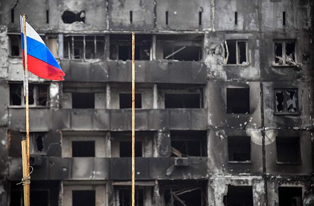 Vor einem zerschossenen Haus in der umkämpften Stadt Mariupol weht die russische Fahne.