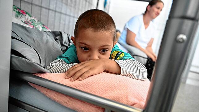 Ein aus der Ukraine geflüchteter Junge sitzt mit seiner Mutter auf einem Bett in einer Notunterkunft in Radolfzell.