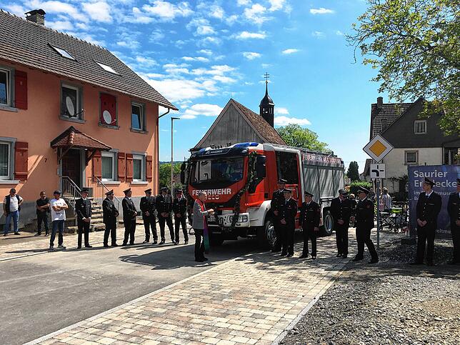 Pfarrer Nikolaus Böhler verteilt großzügig das Weihwasser auf Fahrzeug und Feuerwehrmänner.