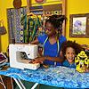 Philadelphia Shayi steht mit dem Bügelbrett und der Nähmaschine im Erlebnisatelier &bdquo;eKhaya&ldquo;. Sie näht ihre Masken aus ...