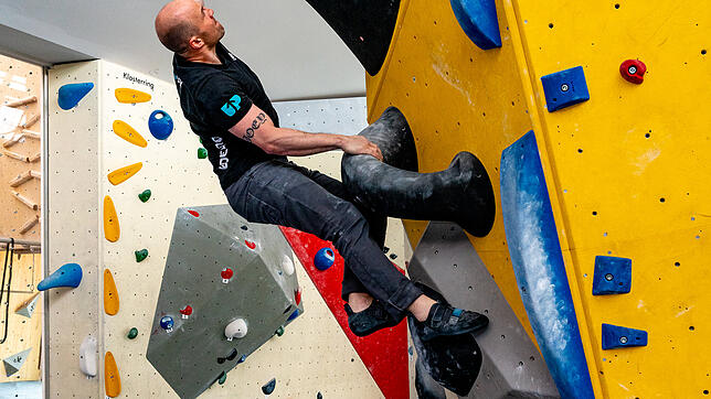 Tim Rothbauer ist im Upjoy für das Routenbauen verantwortlich, hier klettert er an einer schwierigen schwarzen Route, nur weiß ...