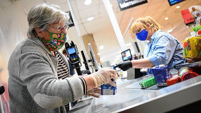 Eine Kundin mit Mund-Nasen-Schutz in einem Supermarkt packt ihre Einkäufe ein. Dass das Tragen der Maske zur Immunisierung gegen das ...