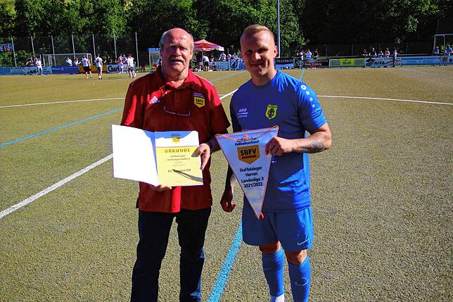 Landesliga-Staffelleiter Franz-Josef Grüninger überreicht den Meisterwimpel an den Singener Kapitän Sven Körner