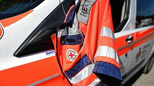 Eine Jacke eines Rettungssanitäters des Deutschen Roten Kreuzes hängt am Fenster eines Krankenwagens. (Symbolbild)