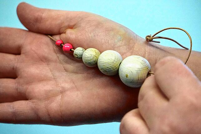 Die blinden Untersucherinnen können Knoten in der Brust von wenigen Millimetern, so wie die rosa Kügelchen auf dieser Schnur, ertasten. ...