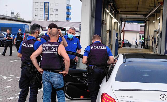 Die Polizisten inspizieren dieses Auto eingehend.