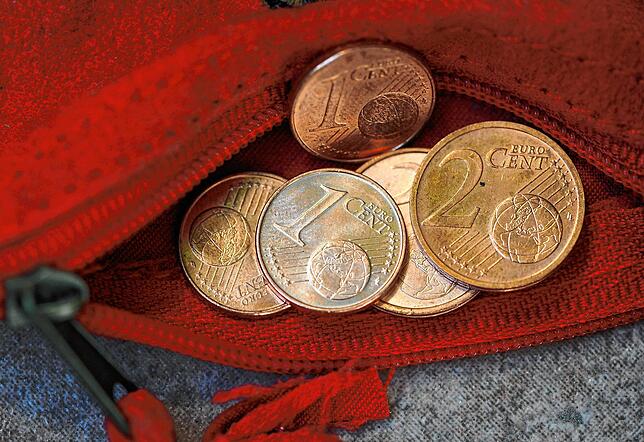 Ein- und Zwei-Cent-Münzen liegen in einer roten Geldbörse. Kinder sollten früh lernen, zu sparen – auch mit kleinen Beträgen.