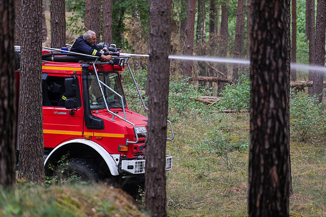 08.07.2019, Mecklenburg-Vorpommern, Alt Jabel: Von einem Feuerwehrfahrzeug löschen Feuerwehrmänner im Wald auf dem ehemaligen ...