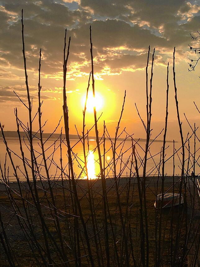Langsam geht die Sonne am Horizont auf und spiegelt sich im Wasser.