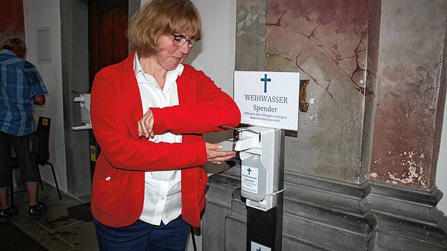 Barbara Koch vom Sekretariat der Wallfahrtskirche Birnau demonstriert, wie man mit Ellenbogen den Weihwasser-Spender bedient.
