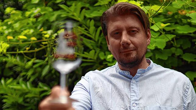 Nikolas Brinkschulte von der Konstanzer Weinfest GbR hält einen Probedruck des Glases für das Konstanzer Weinfest 2023 in die Kamera.