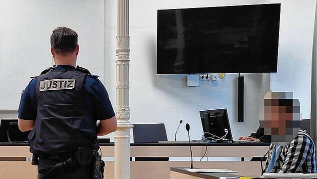 Der 33-Jährige auf der Anklagebank. Ein Justizbeamter hat sich im Gerichtssaal vor ihm positioniert.