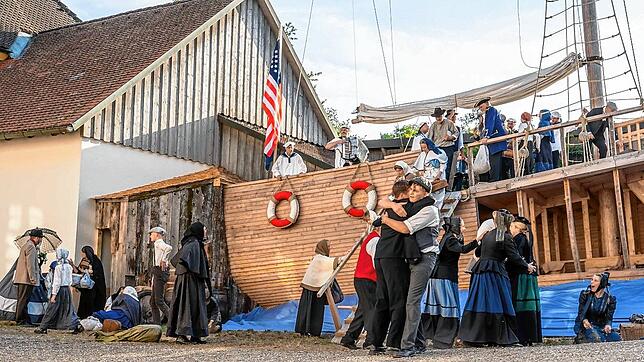 Szenische Darstellung aus dem Theaterstück &bdquo;Zwischen den Welten&ldquo;: Wartende deutsche Auswanderer in einem europäischen Hafen, ...