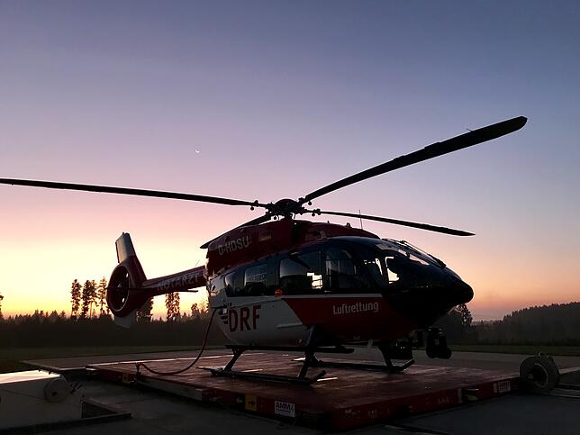 Im Sonnenaufgang wird der Hubschrauber aus dem Hangar gefahren.