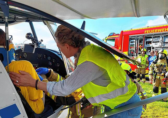 Flugleiterin Minky Schweizer in der gelben Weste betreut eine Verletzte, die noch im Flugzeug sitzt, während ein Feuerwehrmann Blutdruck ...