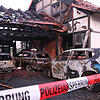 Ausgebrannte Autos stehen in einem Carport zwischen zwei Doppelhaushälften, die durch ein Feuer beschädigt und dadurch nun unbewohnbar ...