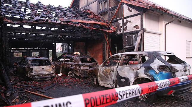 Ausgebrannte Autos stehen in einem Carport zwischen zwei Doppelhaushälften, die durch ein Feuer beschädigt und dadurch nun unbewohnbar ...