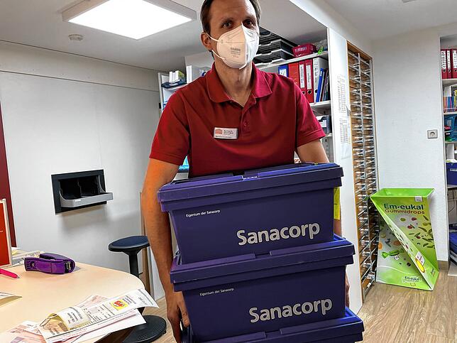 Bernhard Lobmeier trägt die Boxen mit den Impfstoffen und dem Zubehör in sein Büro.