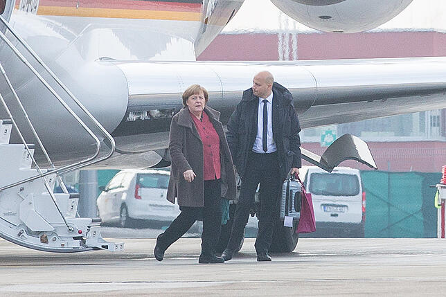 Angela Merkel mit einem Begleiter auf dem Rollfeld.